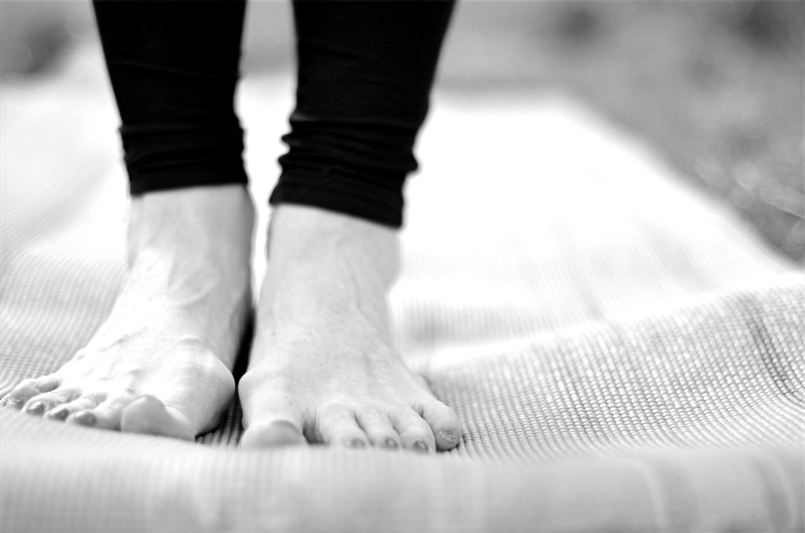 Black and white close-up of bare feet standing on a yoga mat